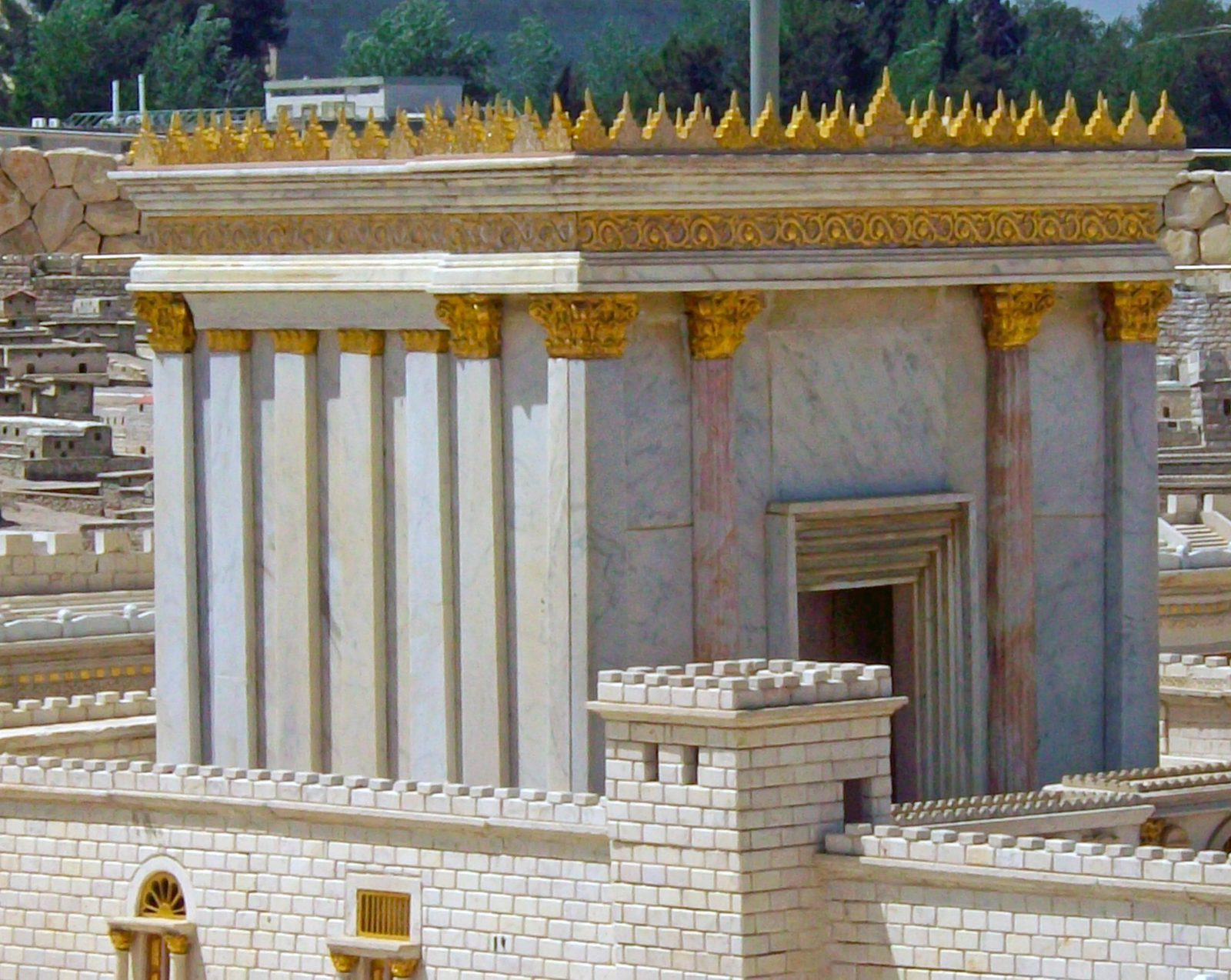 A detailed scale model of the Second Temple — a white stone building with a golden roof, set within walled courtyards
