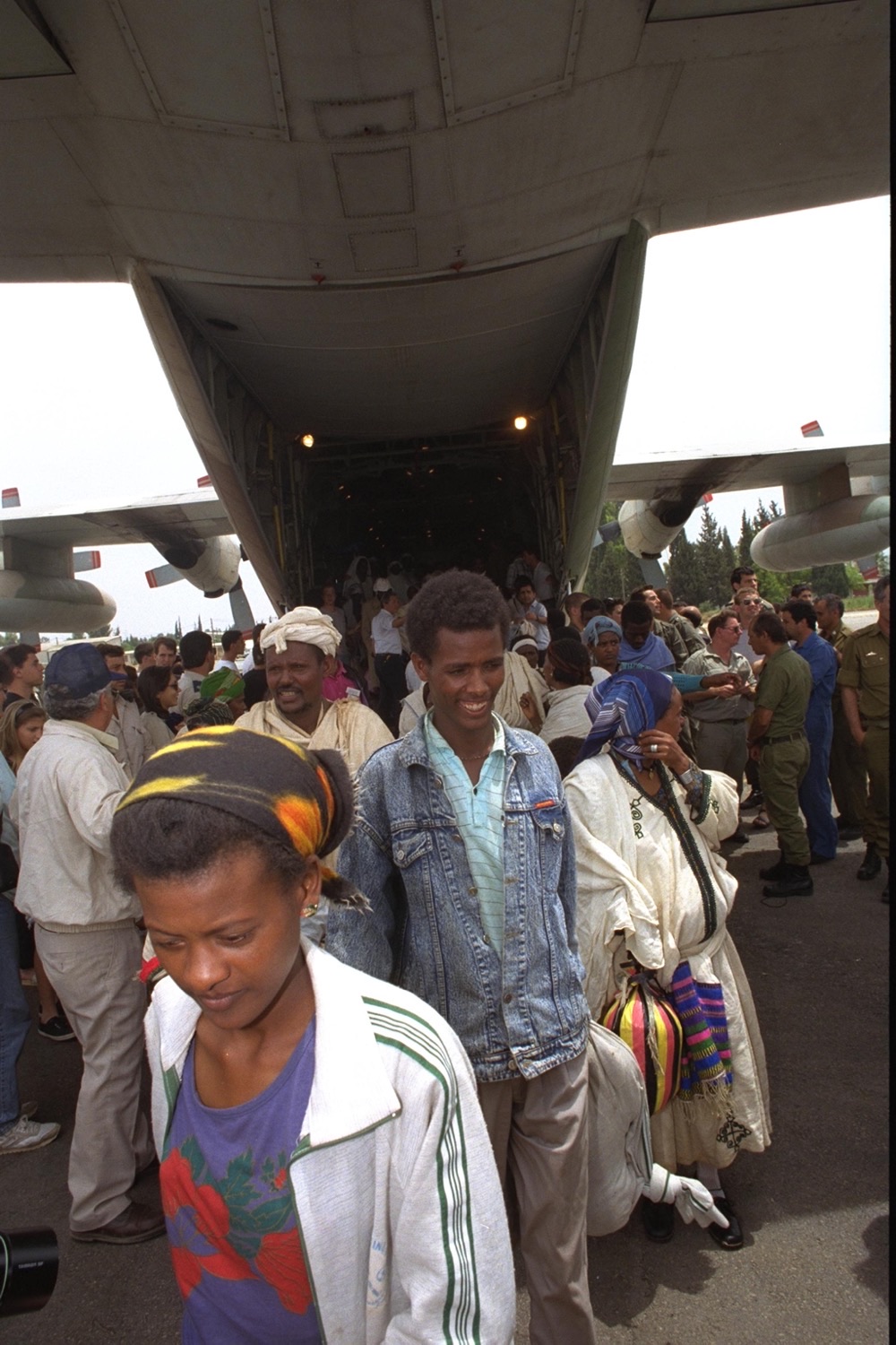 Ethiopian Jewish immigrants walking out of the rear ramp of a military Hercules transport plane, helped by soldiers, during Operation Solomon.