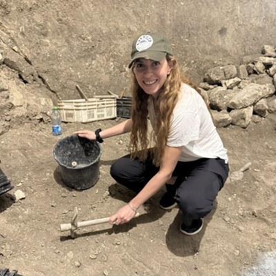 Orit Yakuel at an active archaeological excavation, holding a small pick, during the Dig for a Day program at Beit Guvrim-Maresha, Israel