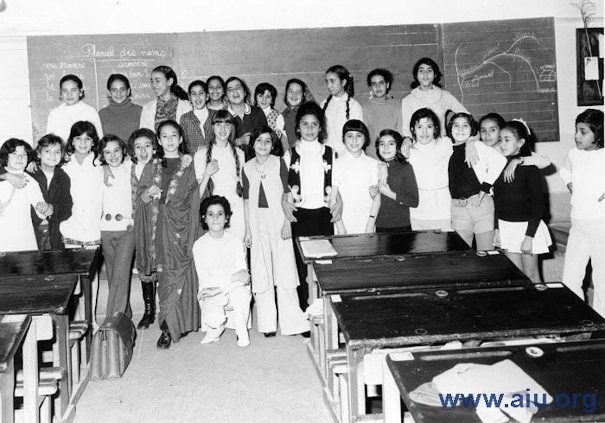 A class of girls posing in a classroom with a French-language chalkboard, at an Alliance Israélite Universelle school in Morocco.