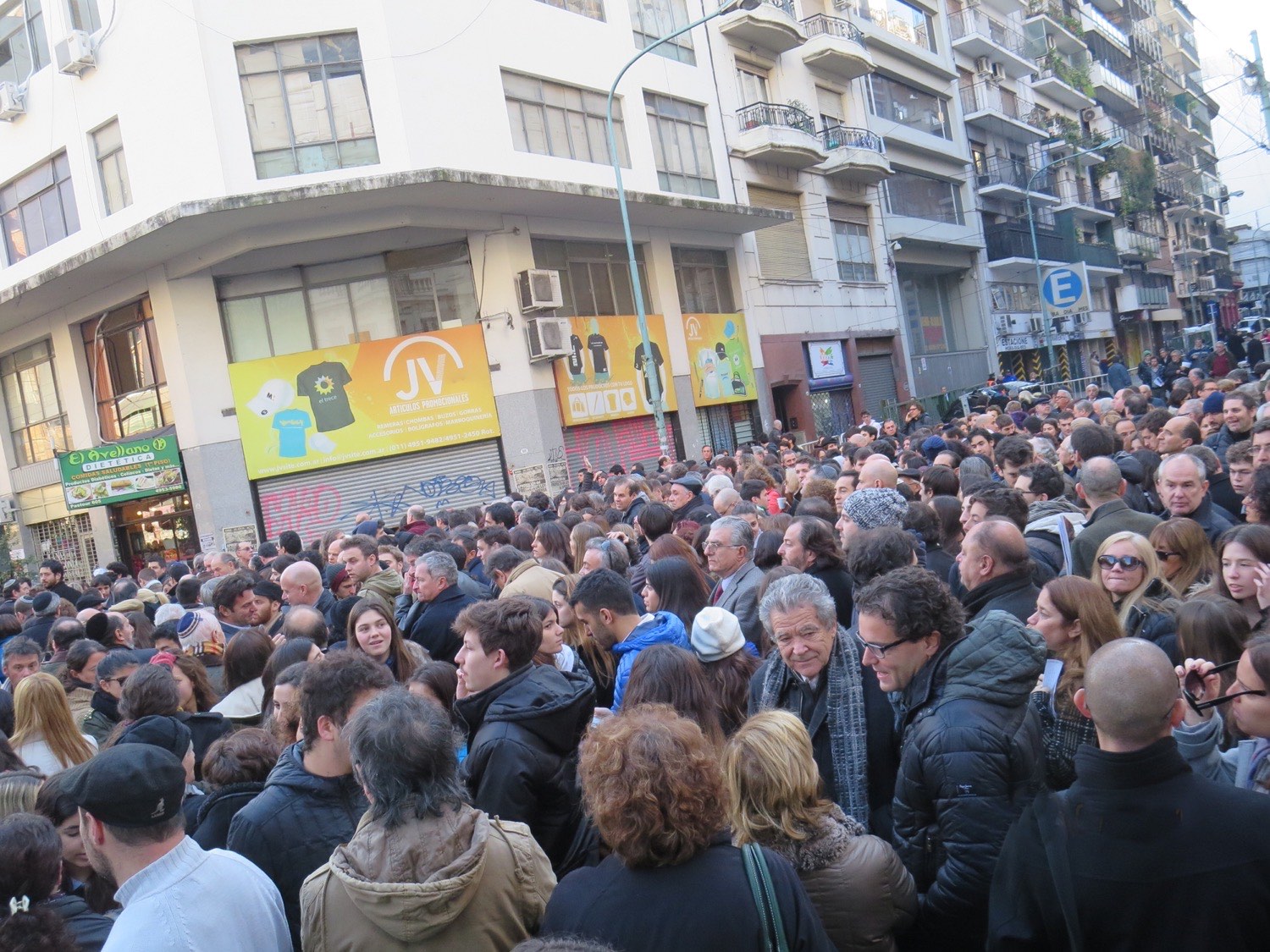 A dense crowd fills a Buenos Aires street at the annual AMIA commemoration, carrying signs and photographs of the victims of the 1994 bombing.