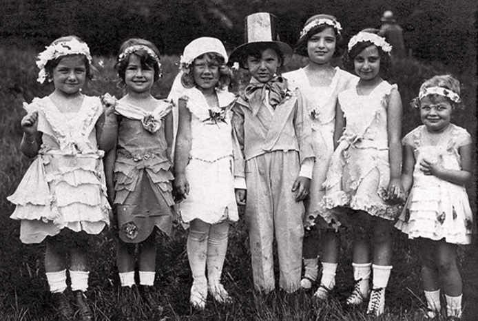 Seven young children in costume standing in a row on the grass at a Jewish kindergarten in Vienna, 1930