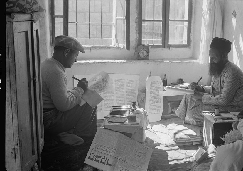 Two Yemenite Jewish scribes, a father and his son, writing a Torah scroll by hand