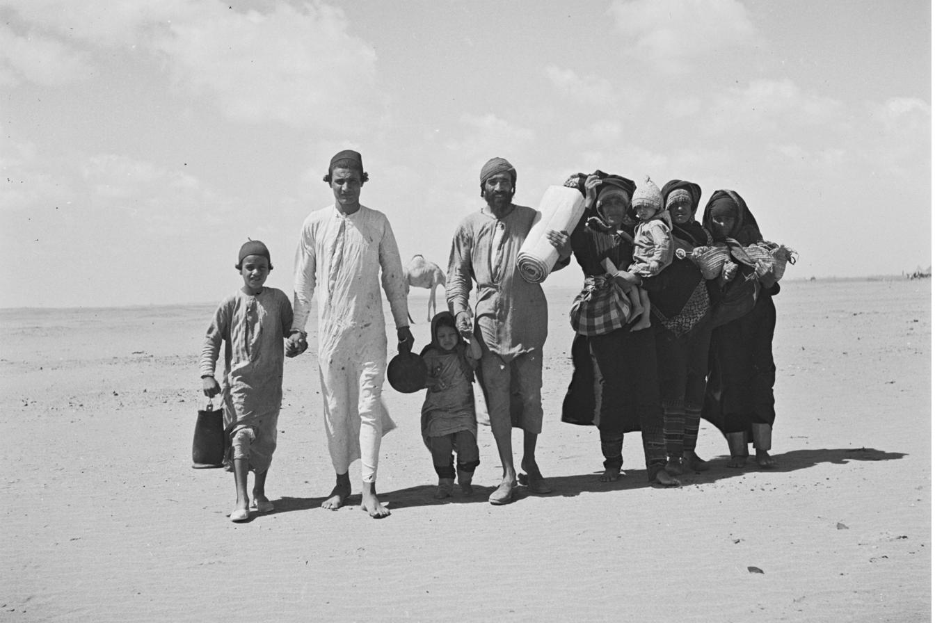 A family with children walking across the desert carrying their belongings, Yemen, 1949
